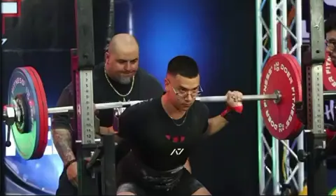Athlete squatting on the competition platform with judges watching