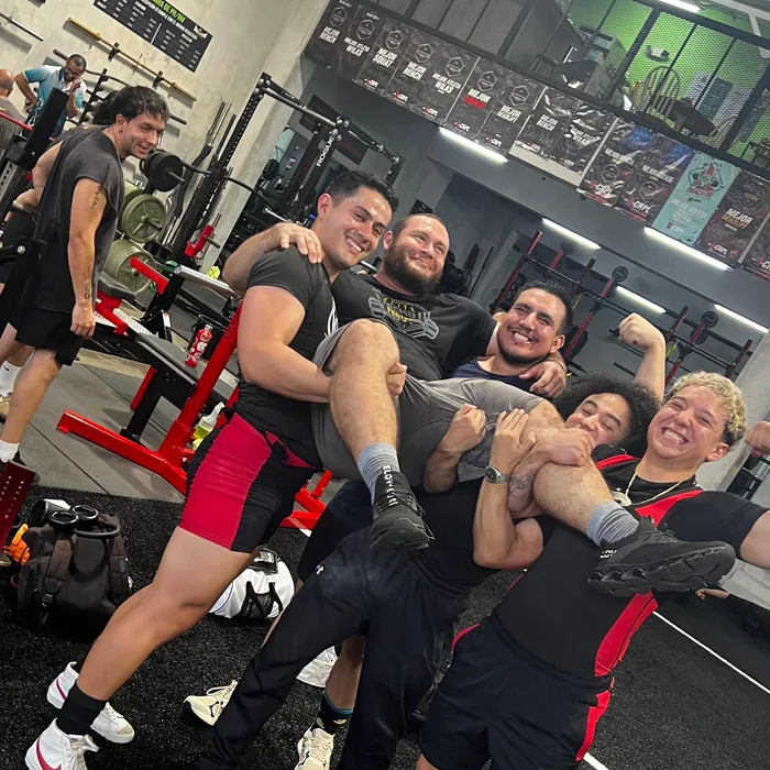 Athletes lifting Douglas Lutz onto their shoulders at the gym after a session